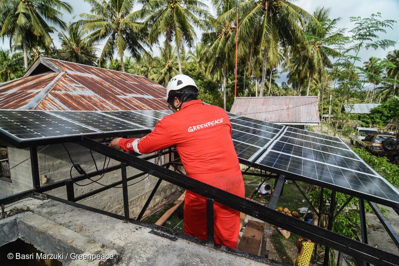 Relawan Greenpeace Indonesia memasang panel surya untuk digunakan sebagai listrik dan pompa air di kamp pengungsi di desa Lero, Donggala, Sulawesi Tengah.