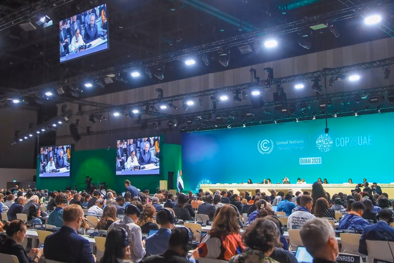 Jumat pagi di Belém, 14 November 2025. Udara di luar Hangar Convention Centre sudah terasa panas dan tegang, bukan hanya karena kelembaban Amazon. Di pintu masuk utama Blue Zone—area steril yang disediakan untuk para negosiator berjas—obrolan diplomatik yang biasa terdengar telah digantikan oleh nyanyian dan tuntutan. Sekitar 90 pengunjuk rasa dari masyarakat adat Munduruku memblokir akses, mengubah diri mereka dari sekadar penonton menjadi inti cerita. Ini bukan side event yang terjadwal; ini adalah intervensi. Masyarakat Munduruku, yang tanah leluhurnya di negara bagian Pará, Amazonas, dan Mato Grosso terancam, tidak datang untuk berfoto. Mereka menuntut satu hal yang mendasar: "diakhirinya proyek dan kegiatan ekstraktif yang mengancam wilayah adat," terutama di cekungan Sungai Tapajós dan Xingu. Adegan ini adalah ironi pertama dan paling tajam dari KTT iklim PBB ke-30 ini. Presiden Brasil, Luiz Inácio Lula da Silva, telah dengan lantang menjanjikan KTT ini sebagai "COP of Truth" ("COP Kebenaran"). Namun, ketika "kebenaran" dari garis depan krisis iklim tiba di gerbangnya, respons resmi bukanlah dialog, melainkan pemanggilan tentara untuk memperkuat keamanan. Di dalam, di balik barikade, dunianya terasa berbeda. Joni Aswira Putra Ketua Umum Masyarakat Jurnalis Lingkungan Indonesia (The Society of Indonesian Environmental Journalist), melaporkan untuk Ekuatorial dari Belém. Ia menggambarkan negosiasi minggu pertama, yang berakhir pada Sabtu, 15 November 2025 , sebagai "cukup dinamis". "Dinamis" adalah kata yang sopan untuk "penuh konflik". Di balik "banyak side event" dan "pertemuan-pertemuan presidensi" yang diamati Joni, dua pertarungan fundamental sedang berkecamuk. Pertarungan pertama adalah soal uang: pertarungan triliunan dolar mengenai siapa yang membayar untuk transisi iklim. Pertarungan kedua adalah soal kredibilitas: pertarungan eksistensial mengenai integritas tuan rumah yang menjanjikan penyelamatan Amazon sambil berencana mengebor minyak di muaranya. Direktur Eksekutif COP30, Ana Toni, berusaha meredakan ketegangan, menyebut protes Munduruku sebagai "sah" dan meyakinkan media bahwa pemerintah "mendengarkan". Namun, tindakan memanggil tentara menceritakan kisah yang berbeda. Ini mengungkap adanya dua COP yang berjalan paralel di Belém: COP di dalam Blue Zone, dengan negosiasi steril dan bahasa teknis; dan COP di luar di jalanan, tempat "kebenaran" yang dituntut Lula sedang diperjuangkan secara fisik. Fakta bahwa masyarakat Munduruku harus memblokir pintu masuk hanya untuk diarahkan bertemu dengan menteri Sônia Guajajara dan Marina Silva membuktikan satu hal: mereka, pada awalnya, tidak didengar sama sekali. Pahlawan Iklim dan rencana pengeboran minyak Presiden Lula adalah pusat gravitasi dari COP30. Di panggung global, dia adalah pahlawan iklim. Dia membuka KTT Pemimpin dengan seruan penuh semangat untuk "kekalahan telak bagi penyangkal iklim". Seperti yang dicatat oleh Joni Aswira Putra, tuan rumah Brasil dan "Presiden Lula sendiri yang mendorong koalisi besar" untuk mengakhiri ketergantungan dunia pada bahan bakar fosil. Ada "kabar baik" yang nyata untuk mendukung retorikanya. Pemerintahannya telah mencapai kemajuan yang mengesankan dalam menekan laju perusakan hutan. Angka deforestasi di Amazon Brasil telah turun sebesar 50% selama tiga tahun masa jabatannya. Ini adalah pencapaian signifikan yang dipamerkan di KTT. Inisiatif utamanya adalah 'Tropical Forest Forever Facility' (TFFF), sebuah mekanisme pendanaan baru yang dirancang untuk membuat "hutan yang berdiri lebih berharga daripada lahan yang gundul". TFFF bertujuan mengumpulkan $125 miliar untuk perlindungan hutan, dan telah mendapatkan komitmen awal $5,5 miliar, termasuk dari Norwegia dan kontribusi dari Brasil sendiri. Namun, seperti yang diakui Lula sendiri dalam pidatonya, ada "kesulitan dan kontradiksi". Kontradiksi-kontradiksi ini begitu mencolok sehingga mengancam kredibilitas seluruh KTT. Kontradiksi Minyak. Hanya beberapa minggu sebelum COP30 dimulai, pemerintahannya menyetujui lisensi pengeboran minyak dan gas di Foz do Amazonas, sebuah wilayah sensitif di lepas pantai muara Sungai Amazon. Ini adalah langkah yang dikecam para kritikus sebagai kemunafikan yang mencengangkan. Kontradiksi Infrastruktur: Secara bersamaan, pemerintahannya mendorong "peningkatan" jalan raya BR-319, sebuah proyek yang akan membelah wilayah barat Amazon yang masih utuh. Para ilmuwan memperingatkan ini akan memberikan "tekanan yang belum pernah terjadi sebelumnya" dari agribisnis dan ekstraktivisme. Ada pula rencana untuk "de-statise" (privatisasi) sungai-sungai utama seperti Tapajós untuk menciptakan "hydrovia" (jalur air) bagi pengiriman kedelai. Kontradiksi Politik Lula harus melakukan "tindakan penyeimbangan" politik yang berbahaya. Untuk memerintah, ia bergantung pada dukungan lobi "Ruralista" (agribisnis) yang kuat, yang mendominasi Kongres dan mendorong agenda ekstraktif yang berlawanan langsung dengan konservasi. Kontradiksi Ambisi Brasil, yang memposisikan diri sebagai pemimpin iklim global, secara bersamaan adalah salah satu emiten teratas dunia dan secara aktif mempertimbangkan untuk bergabung dengan OPEC+, aliansi negara-negara produsen minyak. Ini bukan sekadar "tindakan penyeimbangan"; ini adalah strategi ganda yang terkompartementalisasi. Lula tidak sedang menyeimbangkan; dia sedang mencoba memiliki keduanya. Di satu sisi, dia memperlakukan Amazon sebagai aset karbon global yang bisa dijual (melalui TFFF) kepada donor internasional untuk pendanaan iklim. Di sisi lain, dia memperlakukannya sebagai aset sumber daya domestik (minyak, tanah, jalur sungai) yang bisa dijual kepada sekutu politik (Ruralista, industri minyak) untuk stabilitas politik dan pembangunan ekonomi "abad ke-20". Paradoks Lula bukanlah kegagalan pribadi; ini adalah model bisnis "Ekstraktivisme Hijau". "COP Kebenaran" adalah panggung global untuk memasarkan kedua strategi yang saling bertentangan ini secara bersamaan. Ini adalah preseden berbahaya yang menunjukkan bahwa perlindungan iklim dan ekstraktivisme dapat berjalan beriringan, padahal kenyataannya keduanya saling meniadakan. Keuangan transisi Di jantung "dinamika" minggu pertama yang dilaporkan Joni Aswira Putra untuk Ekuatorial adalah satu isu yang selalu menjadi kunci: "keuangan transisi". Ini adalah medan pertempuran utama yang memecah belah Global Utara dan Global Selatan, dan di Belém, pertarungan ini berpusat pada dua mekanisme yang saling terkait: "Pasal 9 dari Perjanjian Paris" dan "Peta Jalan Baku-Belem" yang baru. Pasal 9 adalah inti dari ketidakpercayaan. Secara hukum, pasal ini mewajibkan negara-negara maju untuk menyediakan sumber daya keuangan bagi negara-negara berkembang untuk mitigasi dan adaptasi. Kata kerja yang digunakan adalah "shall provide" (harus menyediakan), sebuah kewajiban, bukan saran. Konflik teknis yang sangat politis terjadi pada perbedaan antara Pasal 9.1 dan 9.3. Negara-negara berkembang, yang dipimpin oleh blok G77 dan Tiongkok, berargumen bahwa COP29 di Baku tahun lalu gagal total. Mengapa? Karena kesepakatan di Baku hanya berfokus pada Pasal 9.3: "mobilisasi" keuangan, sebuah istilah yang memungkinkan negara maju menghitung pinjaman swasta dan modal komersial sebagai bagian dari kontribusi mereka. Negara-negara berkembang berargumen bahwa kewajiban inti Pasal 9.1—"penyediaan" dana publik (yaitu, hibah, bukan pinjaman) dari kas negara maju—telah diabaikan dan "masih terutang". Negara-negara maju, khususnya Uni Eropa (UE), diidentifikasi sebagai "penghalang utama" kemajuan dalam perdebatan ini, menghalangi fokus khusus pada pendanaan publik Pasal 9.1. Ke dalam kekacauan inilah "Peta Jalan Baku-Belém" diluncurkan. Ini adalah proposal besar di atas meja: sebuah rencana untuk memobilisasi $1,3 triliun USD per tahun pada tahun 2035. Seperti yang dicatat Joni, tujuannya ambisius: "reformasi arsitektur keuangan dan penghapusan subsidi fosil". Peta jalan ini memang menyerukan "perombakan" sistem keuangan dan "penyaluran kembali" subsidi bahan bakar fosil, yang menurut IMF mencapai angka mengejutkan $7 TRILIUN pada tahun 2022. Namun, peta jalan ini segera dilihat melalui dua lensa yang sangat berbeda. Bagi lembaga-lembaga seperti World Resources Institute (WRI), ini adalah "strategi holistik yang cerdas". WRI memuji "kombinasi pragmatisme dengan fokus pada skala dan perubahan sistem" dan memujinya karena "secara tepat menggeser lensa" dari dana publik yang "sederhana" untuk "membuka aliran yang jauh lebih besar dari investor swasta". Bagi negara-negara Global Selatan, pernyataan WRI adalah perwujudan dari ketakutan terbesar mereka. "Pergeseran lensa" ini, bagi mereka, adalah pengkhianatan terhadap kewajiban hukum Pasal 9.1. Mereka melihatnya sebagai "melemahkan" kewajiban negara maju dan mengganti hibah publik yang mereka butuhkan dengan pinjaman swasta yang hanya akan memperburuk krisis utang. Ini adalah perangkap utang iklim. Negara-negara berkembang, yang sudah menghabiskan 20-30% dari PDB mereka hanya untuk membayar utang, kini dipaksa masuk ke dalam skema di mana mereka harus meminjam uang (modal swasta 9.3) dari negara-negara Utara yang menyebabkan krisis iklim, untuk memperbaiki masalah yang disebabkan oleh negara-negara Utara tersebut, alih-alih menerima dana kewajiban (hibah publik 9.1). Ini adalah bentuk baru kolonialisme iklim. Tanpa penyelesaian kewajiban Pasal 9.1, Peta Jalan $1,3 Triliun berisiko menjadi "laporan yang tidak mengikat dengan dampak terbatas". Ambisi di atas kertas Pertarungan soal uang secara langsung terkait dengan pertarungan soal aksi. Joni Aswira Putra menyoroti fokus utama pada "transition away from fossil fuel" (transisi meninggalkan bahan bakar fosil) dan "peningkatan ambisi NDC" (Kontribusi yang Ditetapkan Secara Nasional). COP30 adalah tenggat waktu krusial bagi negara-negara untuk menyerahkan rencana iklim baru mereka (dikenal sebagai NDC 3.0) yang akan menentukan nasib target 1,5°C. Kebutuhan akan ambisi ini sangat mendesak. Laporan PBB sebelum KTT telah mengkonfirmasi adanya "jurang ambisi yang luas" antara janji-janji saat ini dan apa yang diperlukan. Menanggapi hal ini, sebuah "koalisi yang berkemauan" telah terbentuk. Joni menyebutkan adanya "Belém declaration on fossil fuel" yang didukung oleh 62 negara. Ini merujuk pada "koalisi yang berkembang pesat" dari 62 negara yang kini mendukung "peta jalan transisi bahan bakar fosil (TAFF) yang terstruktur". Ini adalah "koalisi besar" yang didorong oleh Lula, dan cakupannya luas: mencakup Brasil, negara-negara Eropa seperti Prancis dan Jerman, Kenya, dan blok-blok negosiasi penting seperti Aliansi Negara-Negara Kepulauan Kecil (AOSIS). Namun, koalisi 62 negara ini menghadapi kekuatan penentang yang masif. Secara formal, mereka menghadapi perlawanan dari negara-negara seperti Arab Saudi 29 dan produsen batu bara besar seperti Tiongkok dan India, yang menentang bahasa spesifik tentang penghapusan bahan bakar fosil. Namun, perlawanan yang lebih kuat dan lebih meresap bersifat informal. Sebuah analisis baru dari koalisi Kick Big Polluters Out (KBPO) menemukan bahwa lebih dari 1.600 pelobi bahan bakar fosil telah diberikan akses resmi ke COP30. Angka ini sangat mengejutkan: itu berarti satu dari setiap 25 peserta di Belém adalah seorang pelobi industri fosil. Jumlah mereka jauh melampaui delegasi negara mana pun selain tuan rumah Brasil. Selama lima tahun terakhir, 7.000 pelobi fosil telah menghadiri KTT iklim. Konteks ini menjelaskan mengapa peluncuran "Deklarasi Belém tentang Integritas Informasi tentang Perubahan Iklim" menjadi begitu penting. Deklarasi ini, yang didukung oleh 12 negara termasuk Brasil, Prancis, dan Jerman, adalah pengakuan resmi di tingkat COP bahwa negosiasi tidak hanya dirusak oleh lobi, tetapi juga oleh kampanye "disinformasi, pelecehan terhadap suara ahli, [dan] ruang gema yang terpolarisasi". Kampanye ini dirancang khusus untuk "mengulur dan menyabotase aksi" iklim. Pertarungan di Belém bukan lagi sekadar negosiasi kebijakan; ini adalah perang informasi. Para pelobi tidak hanya hadir untuk memengaruhi teks; mereka hadir untuk menciptakan kabut keraguan yang membenarkan kelambanan. Seperti yang dikatakan oleh Lien Vandamme dari Center for International Environmental Law (CIEL), ini bukanlah tata kelola iklim. "Ini adalah penangkapan korporat, bukan tata kelola iklim," tegasnya. Koalisi 62 negara mungkin memiliki otoritas moral, tetapi 1.600 pelobi memiliki anggaran untuk membeli narasi. Indonesia dan dilema 'solusi palsu' Di tengah pertarungan antara Global Utara dan Selatan ini, dalam laporanya kepada Ekuatorial, Joni secara spesifik menyebut Indonesia sebagai negara "Selatan-Selatan" yang, seperti Brasil, berada di posisi kunci untuk menerima pendanaan iklim yang diperdebatkan di bawah Pasal 9. Indonesia datang ke Belém dengan proposal andalannya: "Kebijakan Industri Hijau". Sebagai bagian dari kebijakan ini, pemerintah mempresentasikan 14 proyek pengurangan emisi, yang bertujuan untuk menarik investasi internasional di bawah mekanisme Perjanjian Paris. Namun, para pengamat yang mengikuti kampanye COP Indonesia sebelumnya mencatat adanya "pola yang berulang". Proyek-proyek yang dipresentasikan "seringkali kurang transparan, tidak memiliki jadwal yang jelas, atau strategi implementasi yang terperinci". Kritik paling tajam datang dari dalam negeri. Siaran pers dari Wahana Lingkungan Hidup Indonesia (WALHI) pada 11 November 2025, yang berjudul "Pemerintah Indonesia Gagal Membawa Kepentingan Rakyat Indonesia di COP 30", memberikan analisis yang memberatkan. WALHI mengecam paviliun Indonesia yang baru dibuka sebagai sesuatu yang menyerupai "pasar dagang untuk hutan Indonesia dan sumber daya alamnya". Kritik utamanya ditujukan pada dua pilar strategi Indonesia. Perdagangan karbon sebagai perampasan lahan, dan dekarbonisasi beracun. Analisis WALHI menyimpulkan bahwa komitmen iklim Indonesia (SNDC) "ditakdirkan untuk gagal sejak awal" karena seluruh strukturnya dibangun di atas "skema ekstraktif". Ironisnya, saat Indonesia mempromosikan "solusi" berbasis lahan yang kontroversial, sebuah janji besar lainnya di COP30 menuai kritik serupa. "Belém 4X Pledge on Sustainable Fuels"—sebuah janji yang didukung oleh tuan rumah Brasil, India, Italia, dan Jepang untuk melipatgandakan penggunaan "bahan bakar berkelanjutan" seperti biofuel dan biogas—ditolak mentah-mentah oleh jaringan masyarakat sipil. Climate Action Network (CAN) dan Greenpeace secara eksplisit "Menolak Ikrar Belém 4X". Mereka memperingatkan bahwa ini adalah "distraksi berbahaya" yang akan memicu gelombang baru "penghancuran hutan" global untuk memenuhi permintaan bioenergi. Di sini, Indonesia dan Brasil terlihat sebagai cerminan satu sama lain. Keduanya mempraktikkan model "Ekstraktivisme Hijau". Keduanya menggunakan bahasa "hijau"—baik itu 'Kebijakan Industri Hijau', perdagangan karbon, atau 'Bahan Bakar Berkelanjutan'—untuk menarik pendanaan iklim internasional. Namun, pendanaan tersebut kemudian digunakan untuk melanggengkan model ekonomi ekstraktif yang sama (gas, pertambangan, perkebunan) yang menjadi akar penyebab krisis, dan yang secara konsisten mengorbankan masyarakat adat dan lokal, baik itu Suku Anak Dalam di Jambi maupun masyarakat Munduruku di Belém. Minggu pertama COP30 ditutup dengan "tekanan yang meningkat". Seperti yang dilaporkan Joni Aswira Putra, negosiasinya "dinamis", tetapi para ahli di lapangan, seperti Dr. Rachel Cleetus dari Union of Concerned Scientists (UCS), memperingatkan bahwa "terobosan besar pada topik-topik kritis belum terwujud". Para menteri yang kini tiba di Belém untuk negosiasi tingkat tinggi di minggu kedua mewarisi beban untuk menyelesaikan serangkaian pertanyaan yang belum terjawab. Bagaimana cara menutup "jurang ambisi" emisi untuk menjaga target 1,5°C tetap hidup? Bagaimana cara menyepakati penghapusan bahan bakar fosil yang adil dan didanai—bukan sekadar retorika? Bagaimana cara mengatasi kebuntuan fundamental antara pendanaan publik (Pasal 9.1) dan mobilisasi swasta (Pasal 9.3)? Ada ketakutan yang nyata bahwa proses COP itu sendiri "rusak" dan "tidak lagi sesuai dengan tujuannya". Kekecewaan negara-negara berkembang terhadap hasil tahun lalu di Baku digambarkan sebagai "pengkhianatan yang mengejutkan". Di tengah krisis kredibilitas inilah, Kepala Iklim PBB Simon Stiell memberikan pidato pembukaan yang tajam. Dia memohon kepada para delegasi: "Pekerjaan Anda di sini bukan untuk bertarung satu sama lain – pekerjaan Anda di sini adalah untuk melawan krisis iklim ini, bersama-sama". Saat para menteri mengambil alih negosiasi, "COP Kebenaran" dihadapkan pada pilihan terakhirnya. Kebenaran siapa yang akan mereka wujudkan? Kebenaran yang nyaman dari para pelobi dan solusi palsu mereka? Kebenaran yang dikompromikan dari tuan rumah mereka yang paradoksal? Atau kebenaran yang tidak nyaman dari masyarakat adat Munduruku, yang tuntutannya—jika benar-benar didengarkan—akan memaksa perubahan sistemik yang sebenarnya? Jawabannya akan menentukan apakah Belém dikenang sebagai titik balik, atau hanya sebagai "pasar dagang" lain untuk masa depan planet ini.